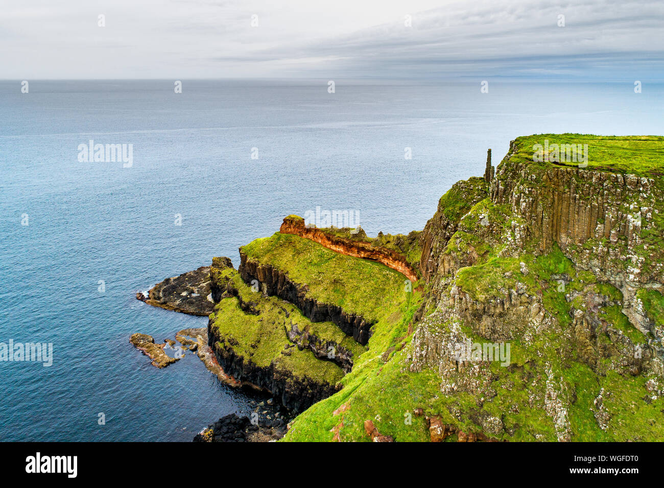 Irlanda del Nord, Regno Unito. Scogliere a costa atlantica nella contea di Antrim con visibile strati geologici e basalto vulcanico formazione di naturale pol esagonale Foto Stock