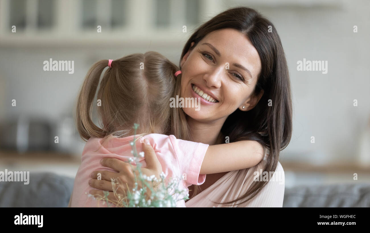 Bella donna azienda fiori abbraccia piccola figlia Foto Stock