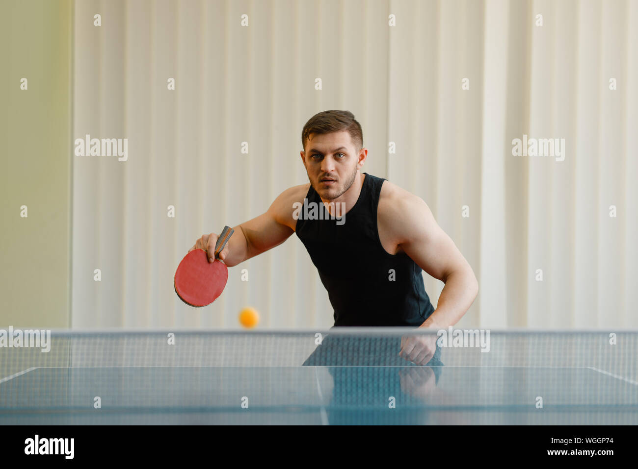 L'uomo con la racchetta e la palla giocando a ping pong per interni Foto Stock