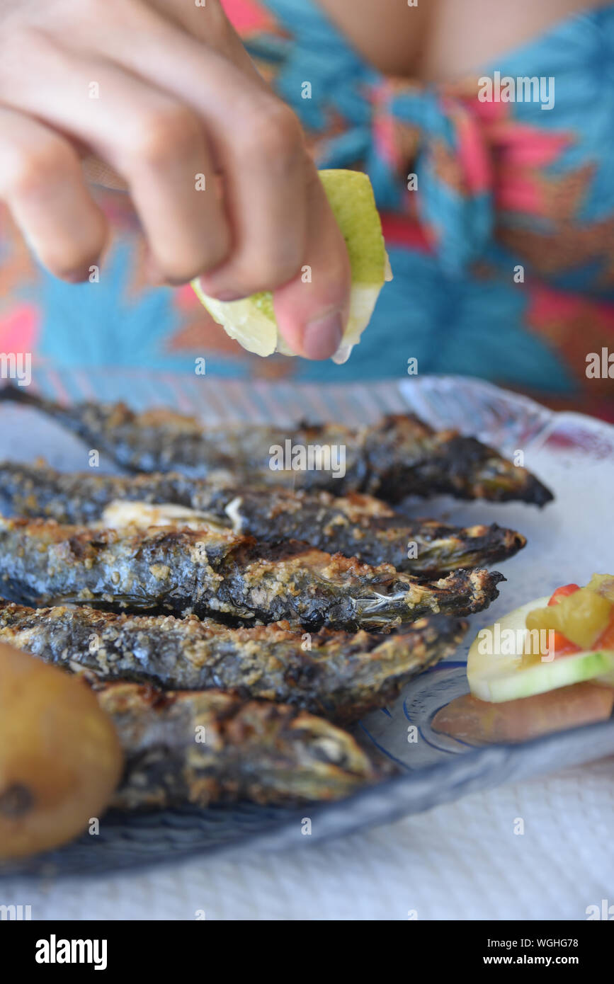 Lison, Portogallo: un diner spreme il succo di limone fresco su Sardine grigliate Foto Stock