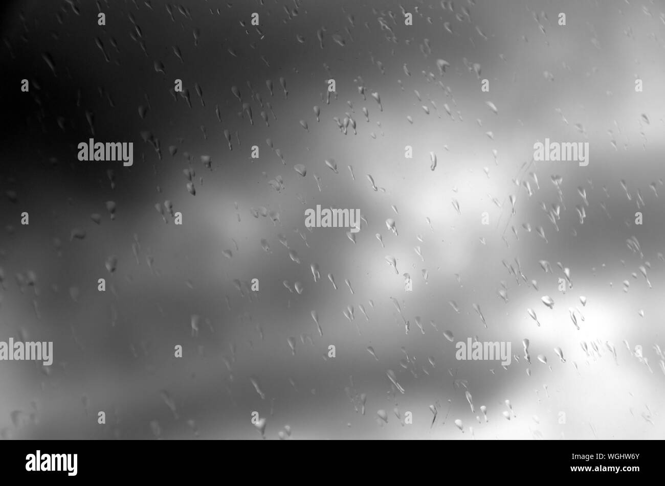 Maltempo - le gocce di pioggia sul vetro del finestrino contro un cielo scuro. Foto Stock
