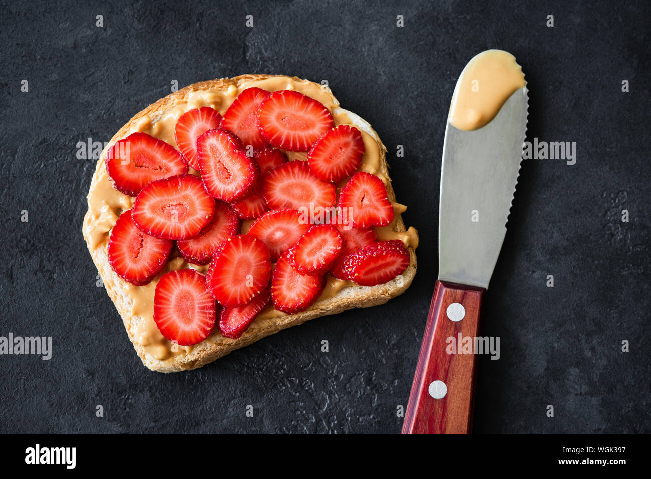 Burro di arachidi toast con fragole fresche su sfondo nero. Vista dall'alto. Più sano PB Jelly sandwich Foto Stock