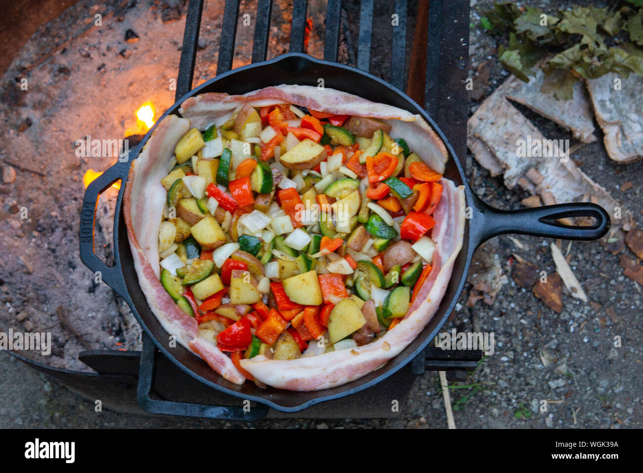 Cena di Cucina su campfire campeggio grill all'aperto verdure carne pancetta Foto Stock