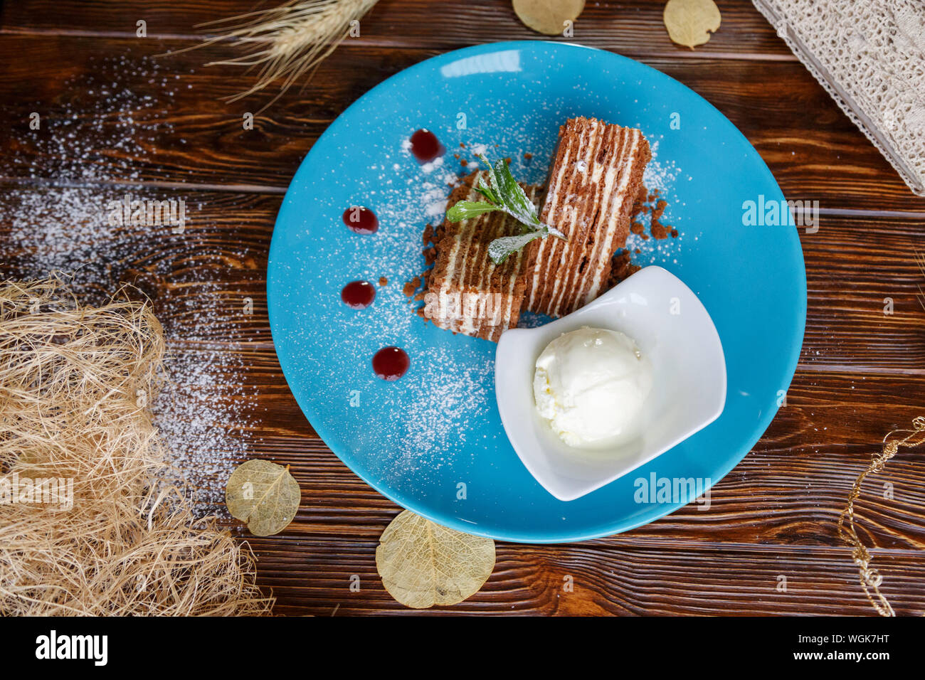 Il gelato e la torta su un piatto di colore blu su un marrone di sfondo di legno Foto Stock