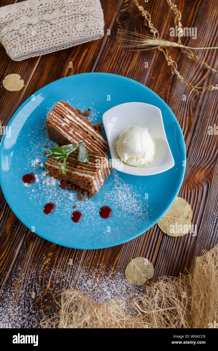 Il gelato e la torta su un piatto di colore blu su un marrone di sfondo di legno Foto Stock