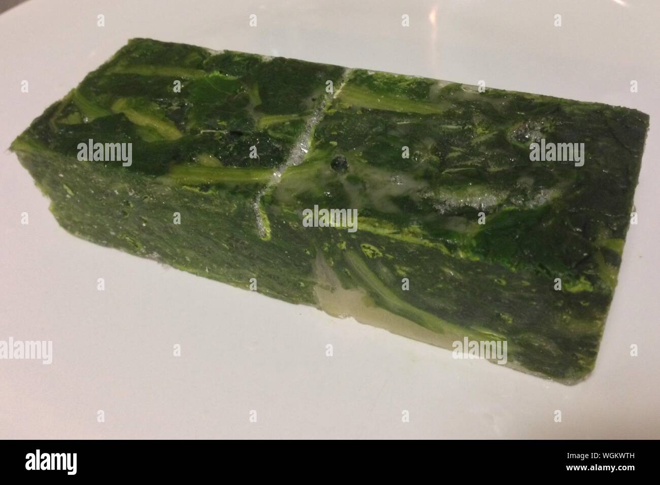 Blocco congelato di spinaci su piastra Foto stock - Alamy