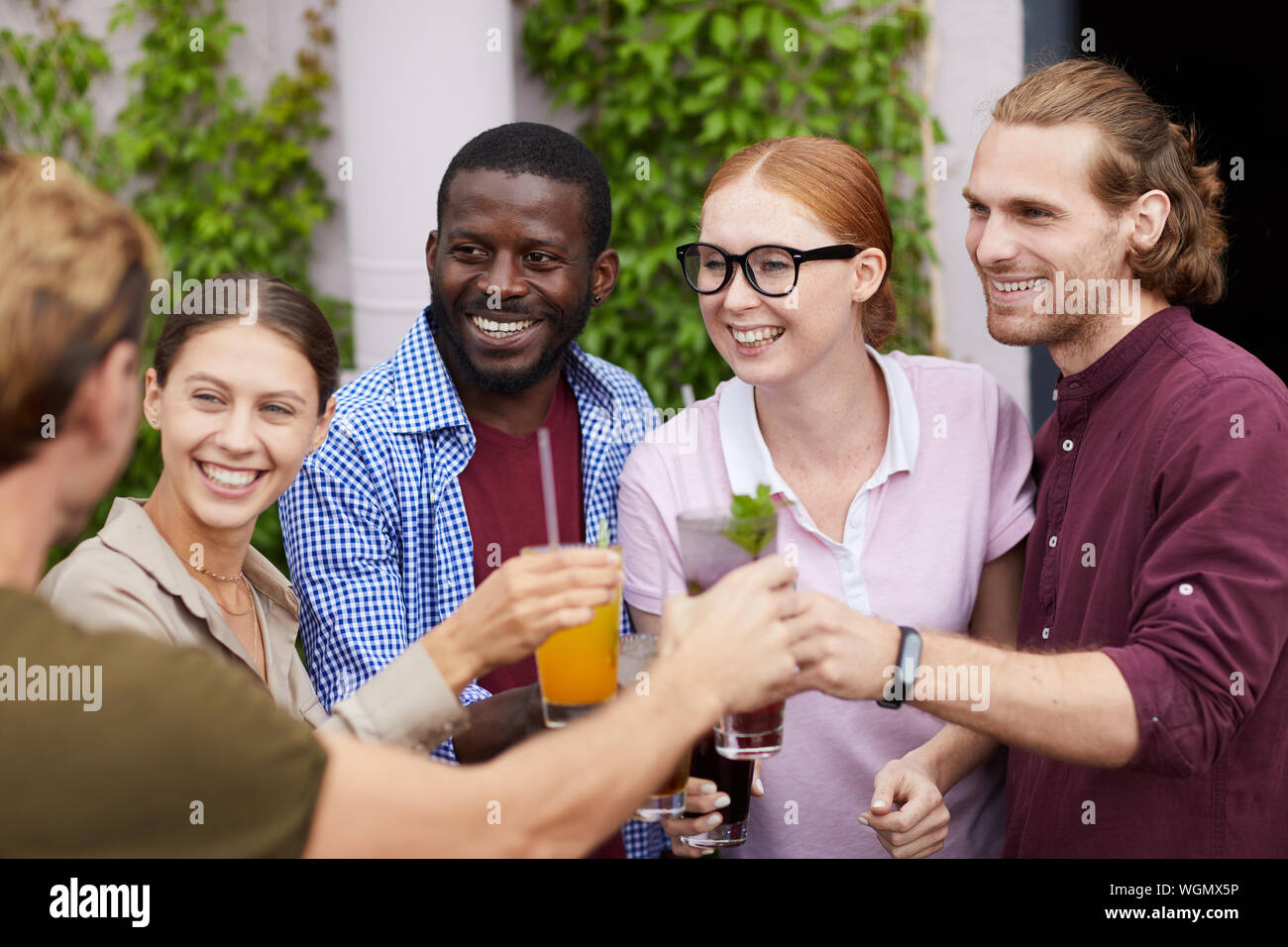 Multi-etnico gruppo di amici bicchieri tintinnanti mentre godendo party all'aperto in estate, spazio di copia Foto Stock