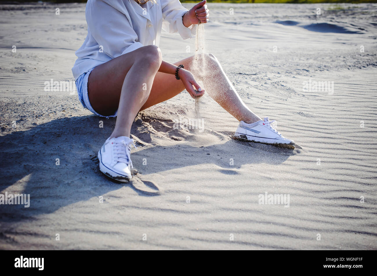 Sezione bassa di donna spargimento sabbia in spiaggia Foto Stock