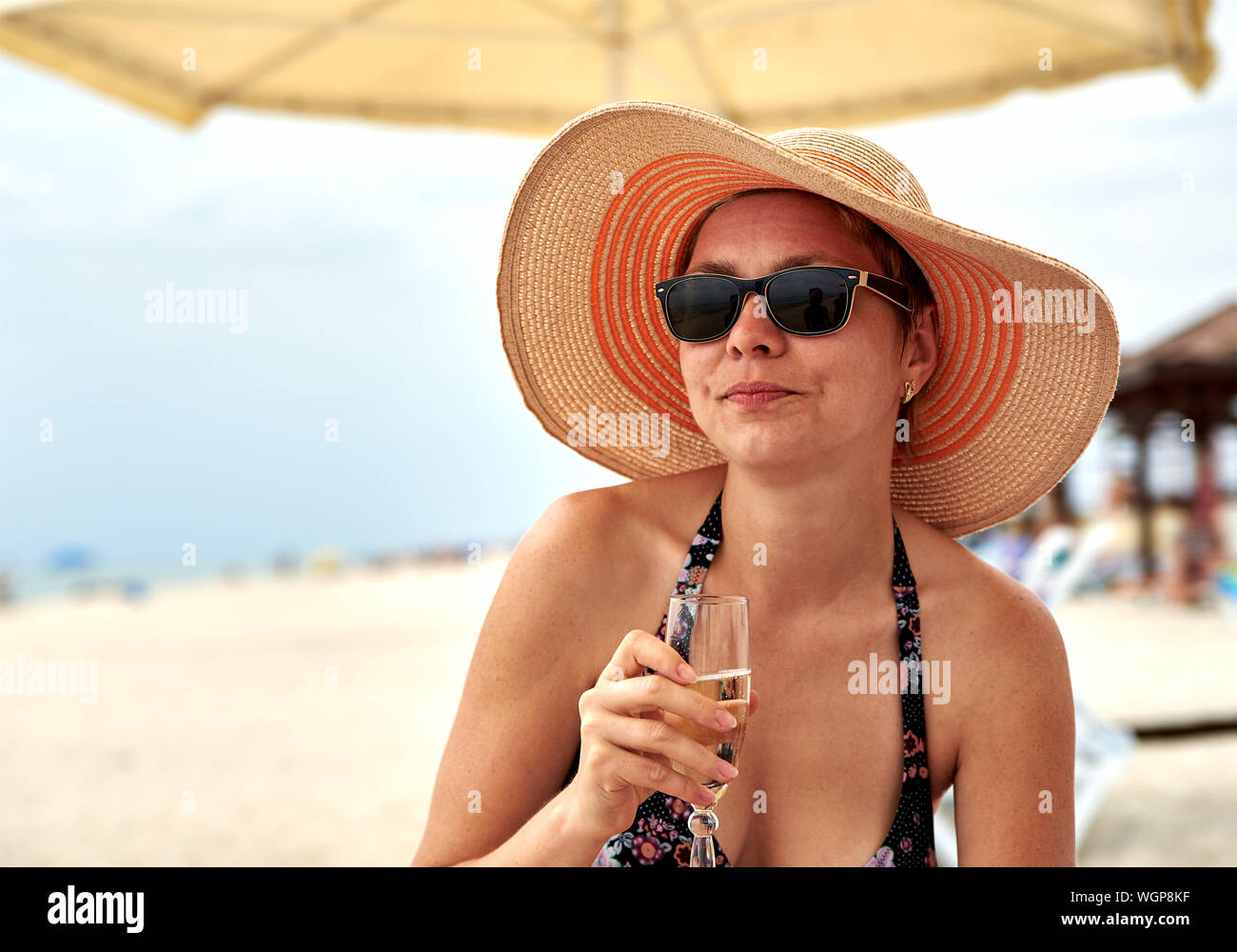 La donna nel cappello per il sole e occhiali da sole tenendo lo Champagne a  spiaggia Foto stock - Alamy