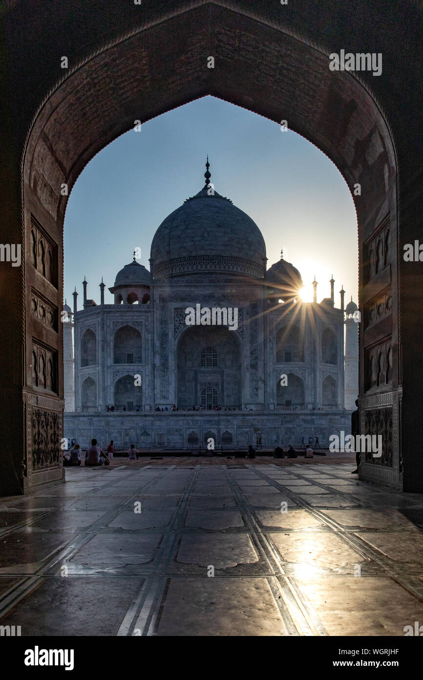 Sunburst appena al di sopra del Taj Mahal visto attraverso l arco della moschea. Foto Stock