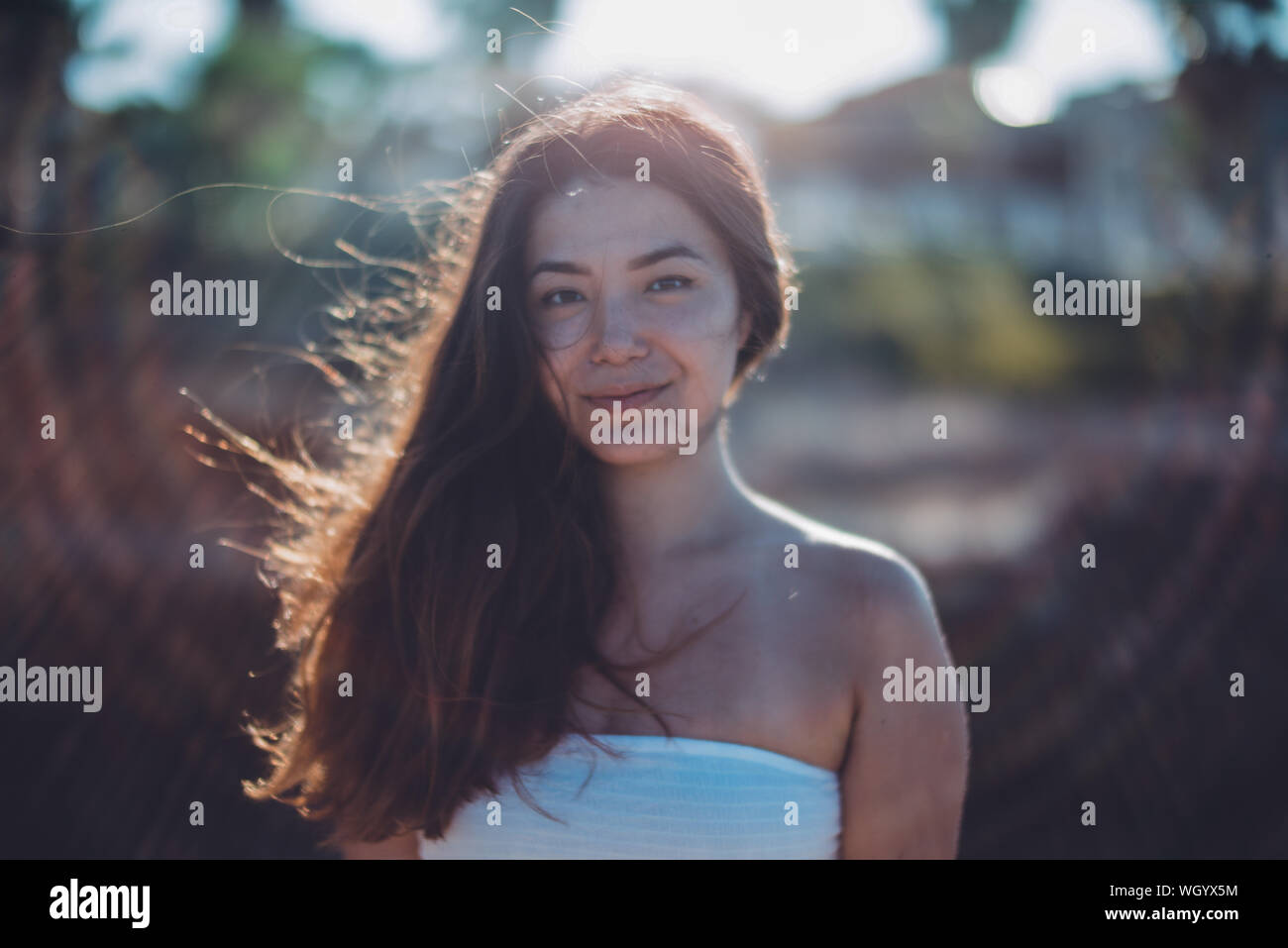 Ritratto di sorridente giovane donna in piedi all'aperto durante la giornata di sole Foto Stock