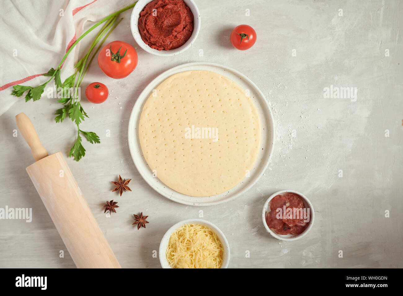 Pasta fresca la base della pizza e gli ingredienti su un tavolo bianco. Vista dall'alto. Foto Stock