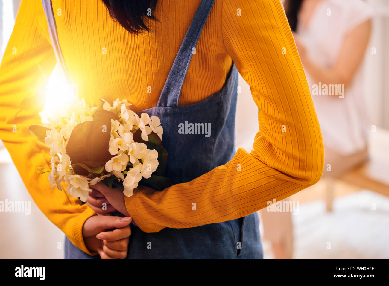 Close-up di un irriconoscibile ragazza adolescente nascondono bellissimi fiori dietro per la piacevole sorpresa di sua madre. La festa della mamma concept Foto Stock
