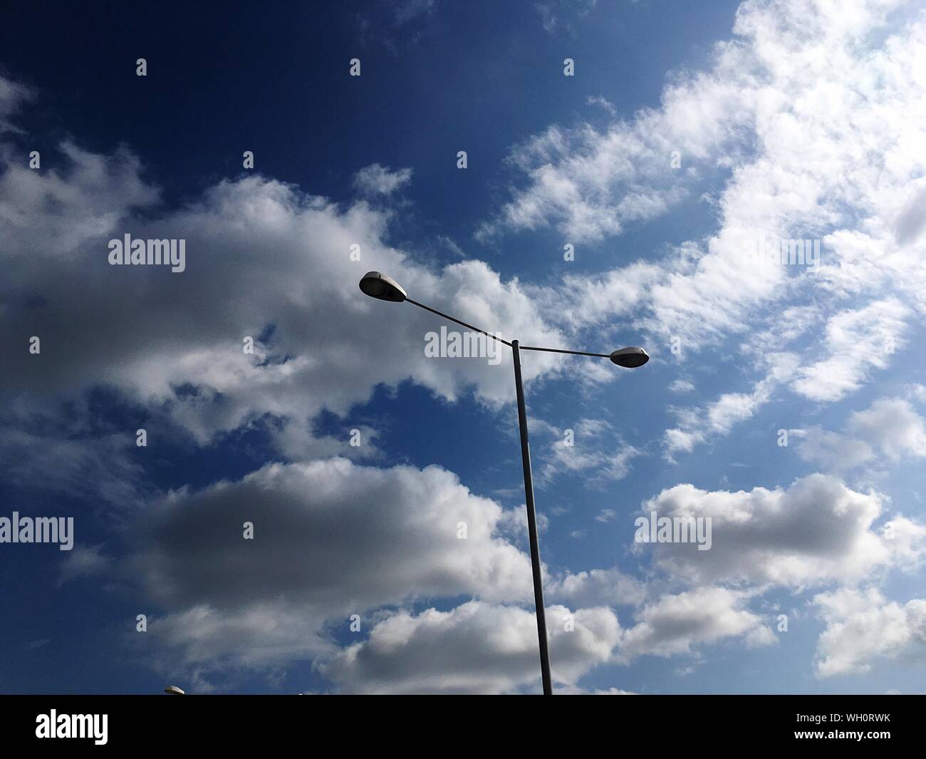 Basso angolo di vista Street Light contro il cielo nuvoloso Durante la giornata di sole Foto Stock
