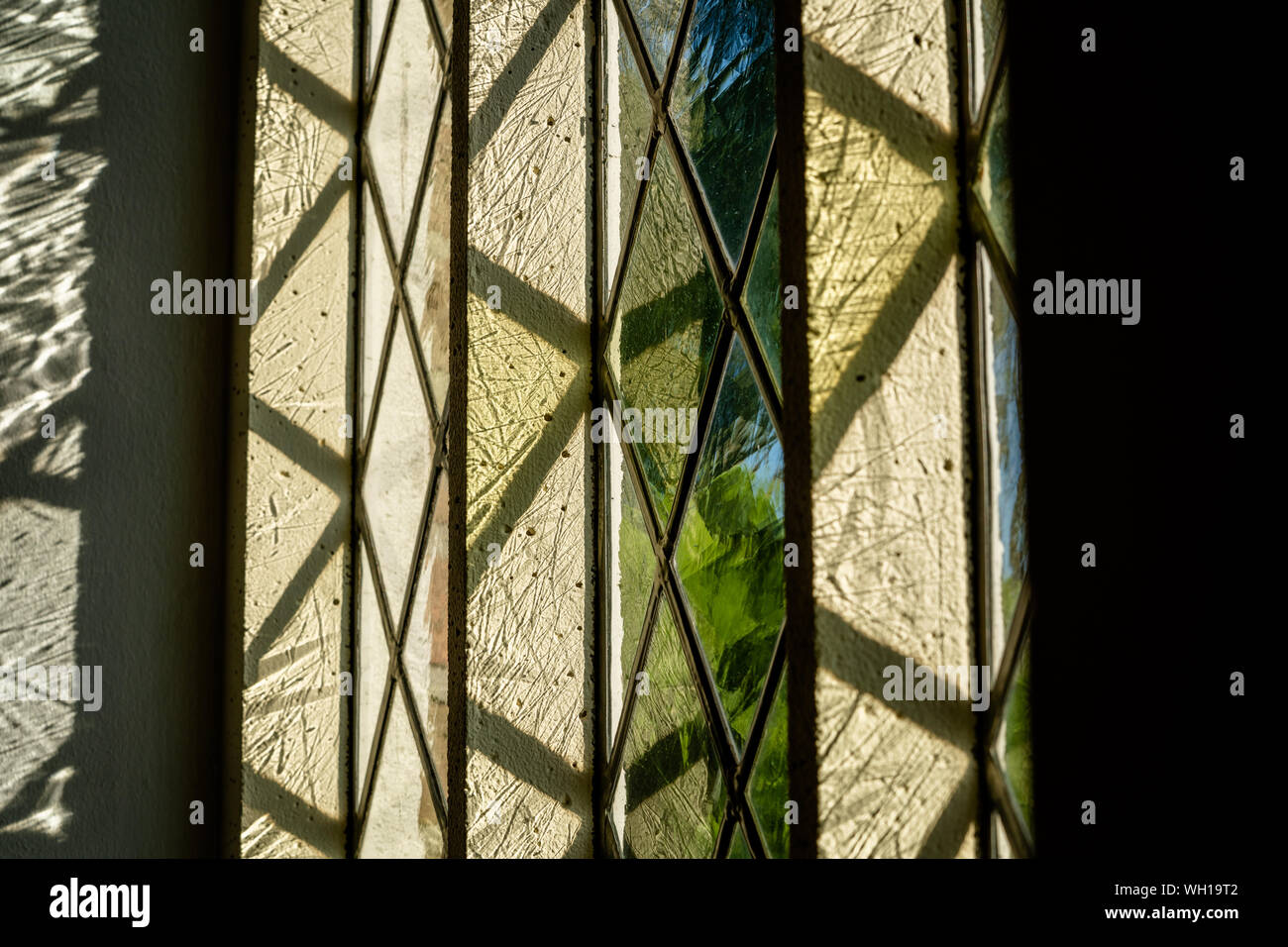 Colorato la luce del sole cade attraverso la finestra di una chiesa edificio con finestre di vetro colorato Foto Stock