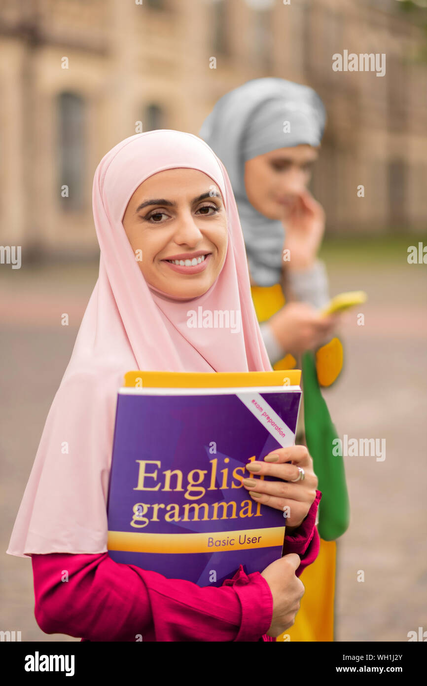 Bella studenti musulmani a sorridere mentre si tiene libri Foto Stock