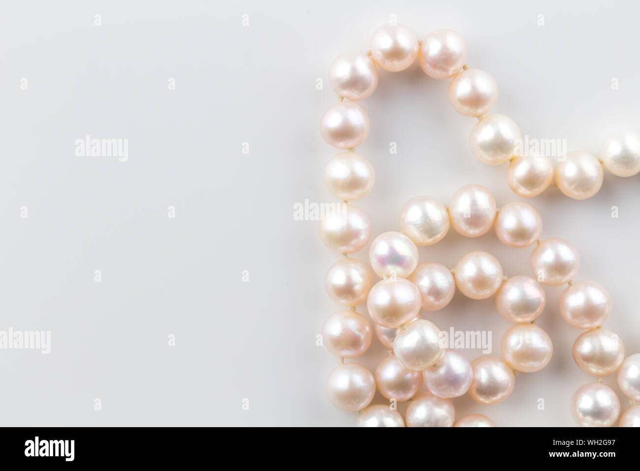 Collana di perle con perle rosa in una stringa isolati su sfondo bianco - vista superiore vicino la fotografia di vere perle oyster Foto Stock