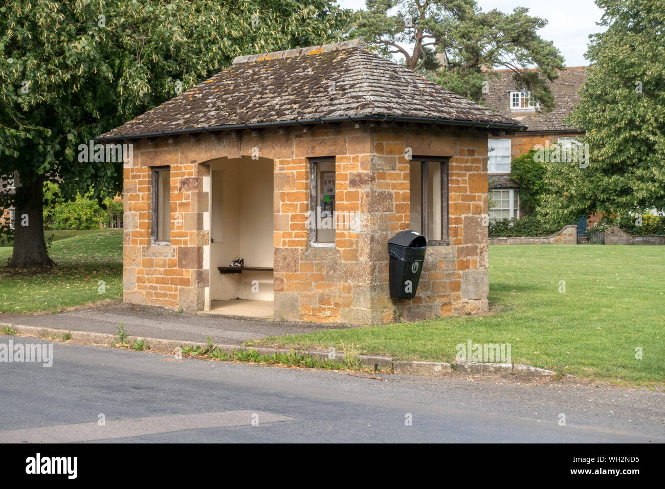 Smart ironstone bus shelter Collyweston con tetto in ardesia nel villaggio di Lyddington, Rutland, England, Regno Unito Foto Stock