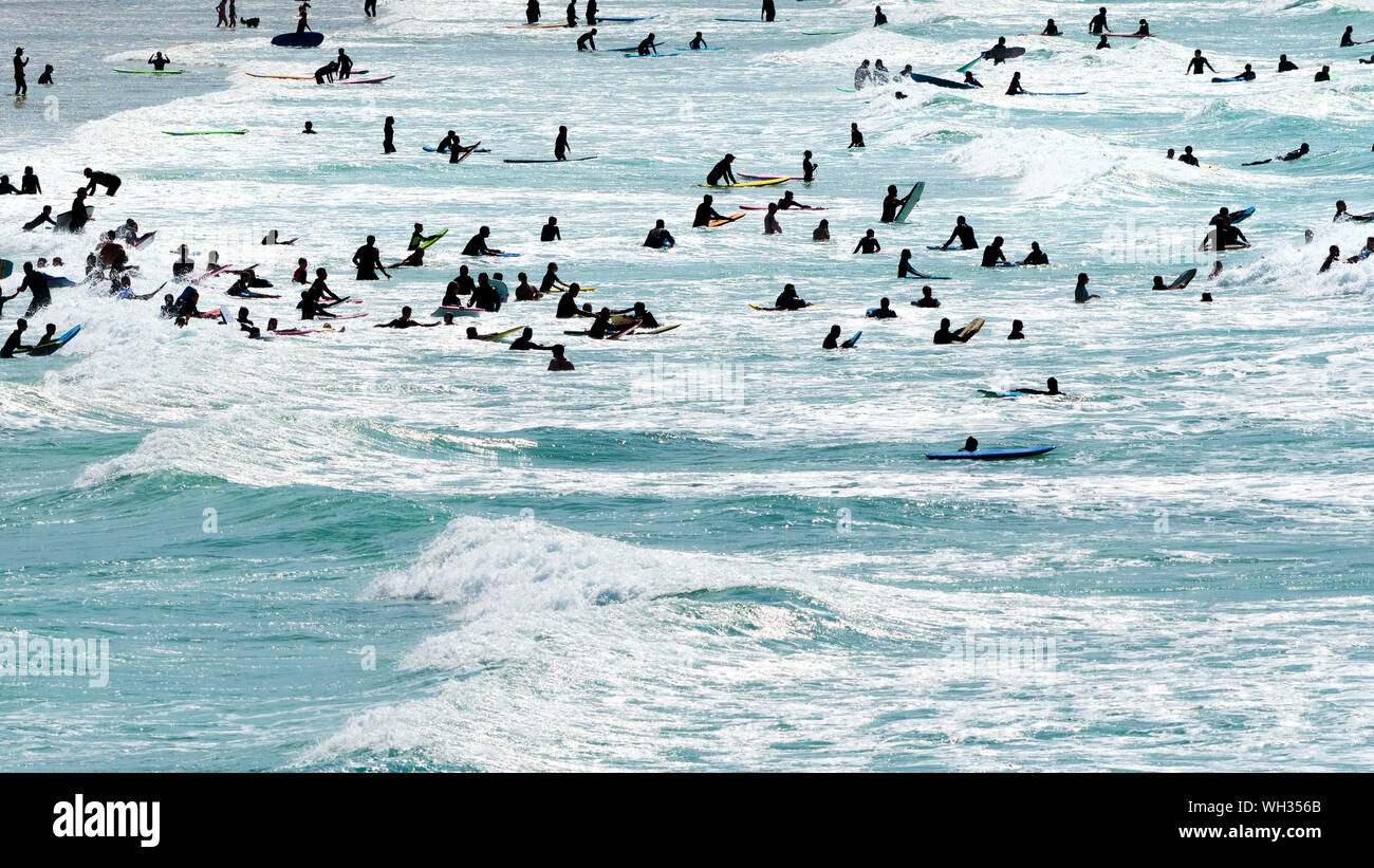 I turisti che si diverte nel mare visto in silhouette a Fistral a Newquay in Cornovaglia. Foto Stock