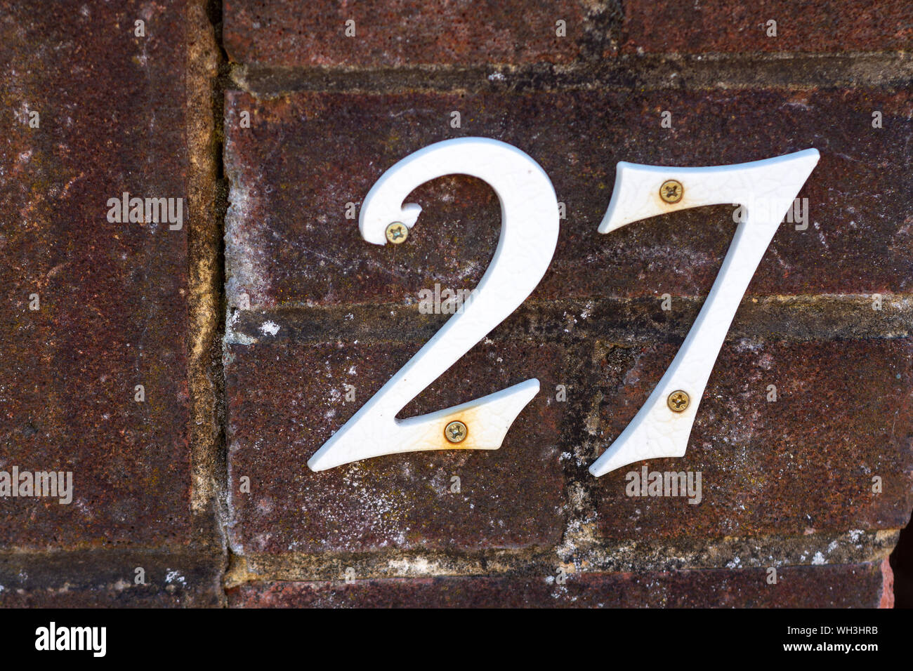 Casa bianca numero 27 su un vecchio muro di mattoni Foto Stock