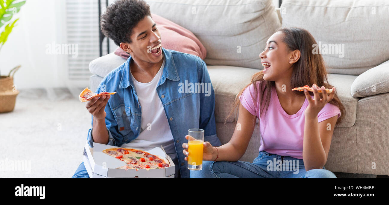 Coppia felice di mangiare la pizza e ridere a casa Foto Stock