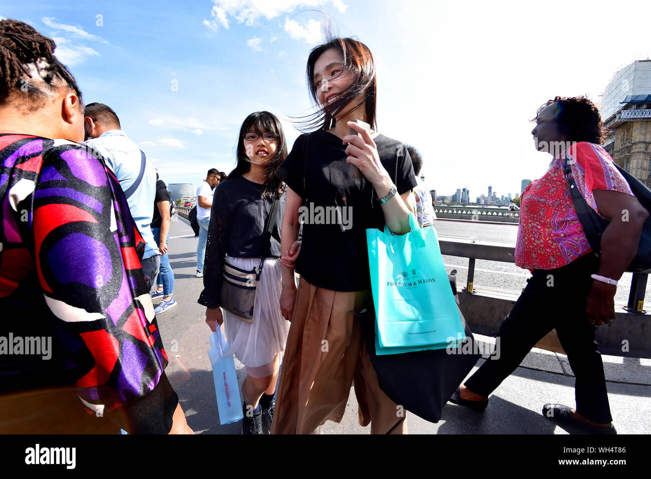 Londra, Inghilterra, Regno Unito. I turisti giapponesi con un Fortnum e Mason borsa di trasporto attraversando il Millennium Bridge Foto Stock