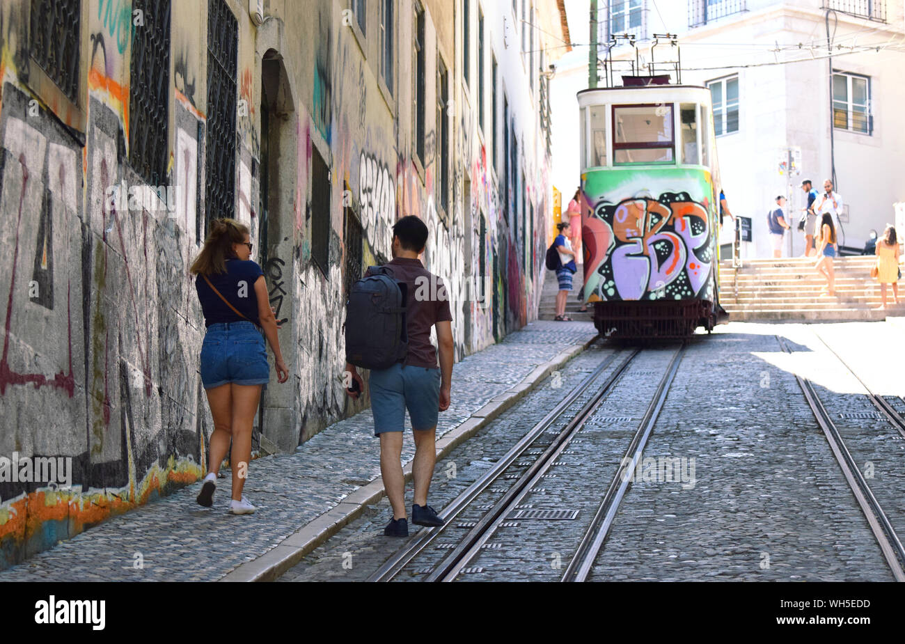 I turisti a piedi fino alla ripida strada acciottolata Rua Da Gloria con la sua famosa funivia noto come ascensor o Elvador da Gloria in background Foto Stock