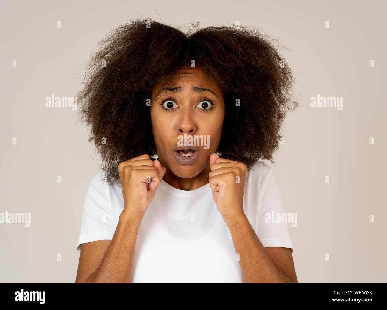 Ritratto di giovane americano africano sentimento donna spaventato e scioccato rendendo la paura, ansia gesti. Guardando terrorizzata la copertura stessa. Copia dello spazio. In Foto Stock