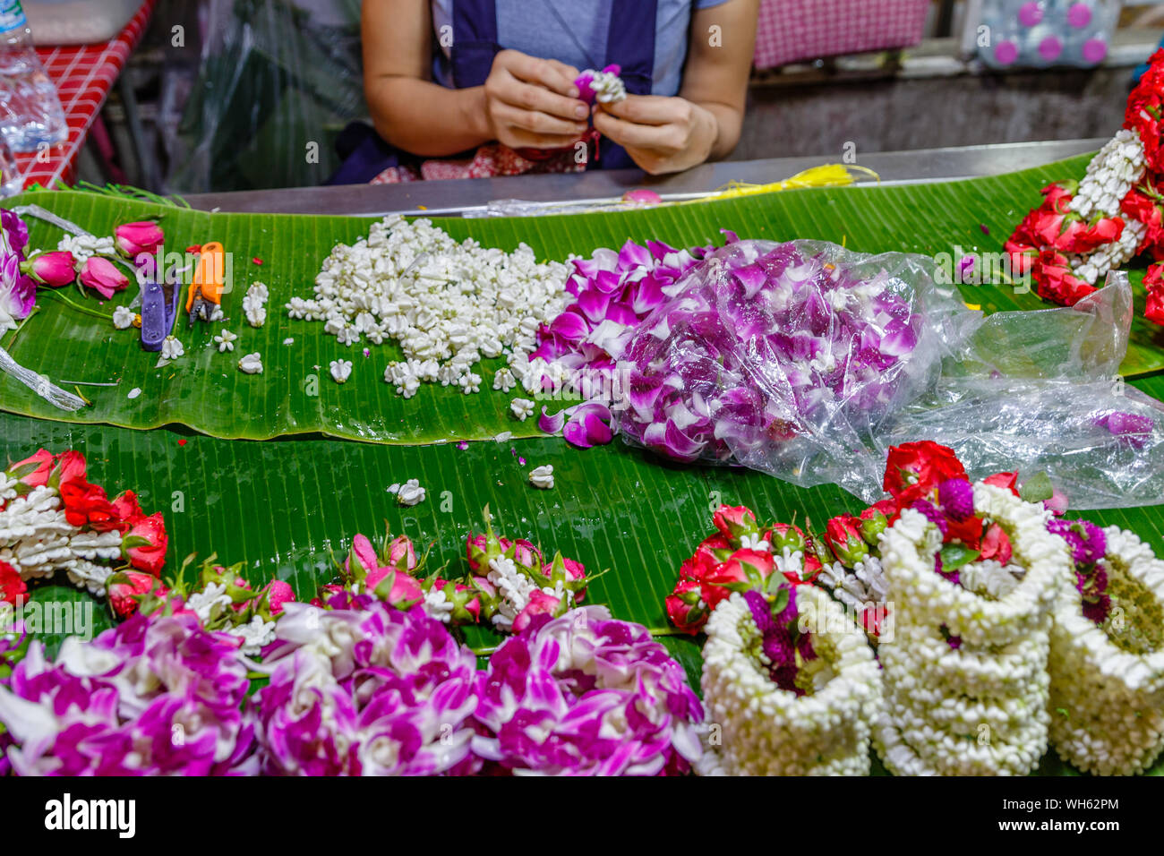Donna fare Phuang malai, tailandese tradizionale ghirlanda di fiori offerte con il gelsomino e orchidee a Pak Khlong Talat, Bangkok il mercato dei fiori. Thailandia. Foto Stock