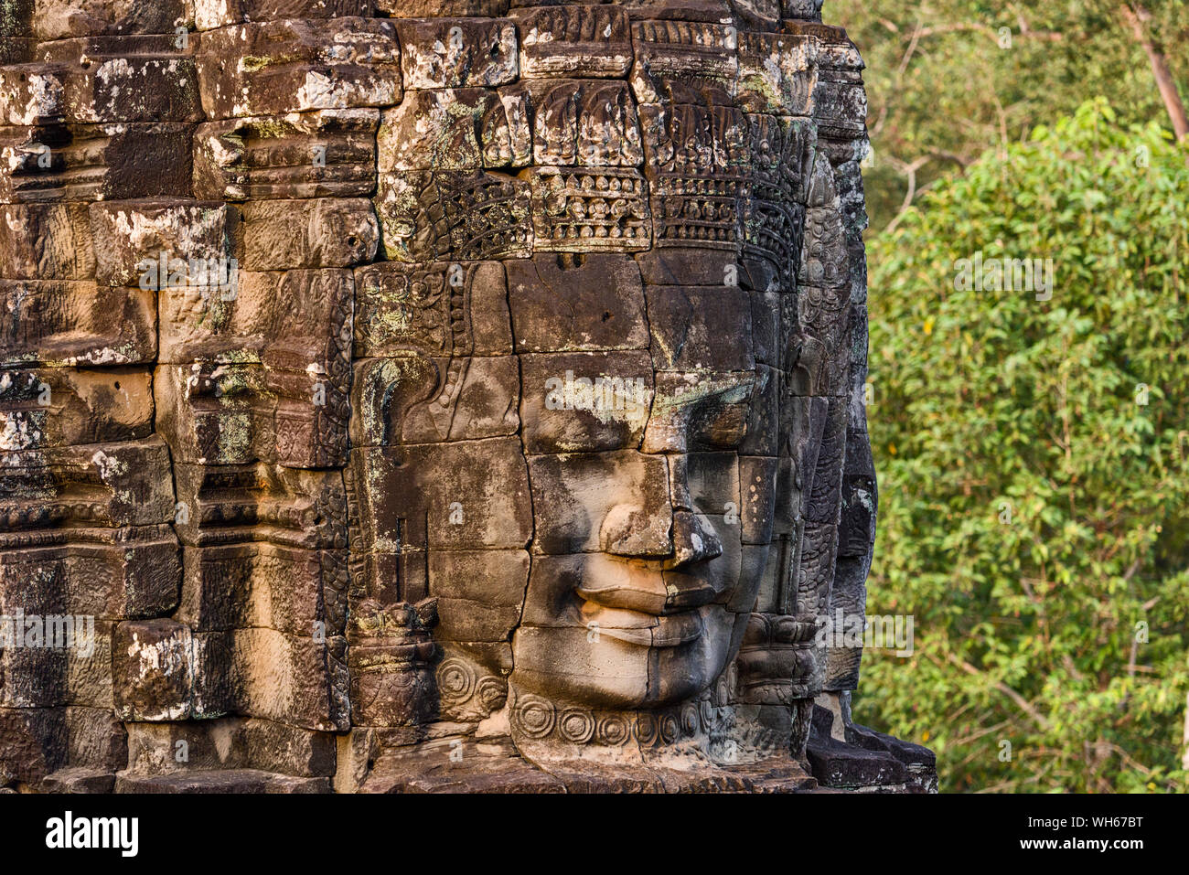 Enigmatica e sorridenti facce di pietra di Buddha giganti al tempio Bayon in Siem Reap, Cambogia Foto Stock