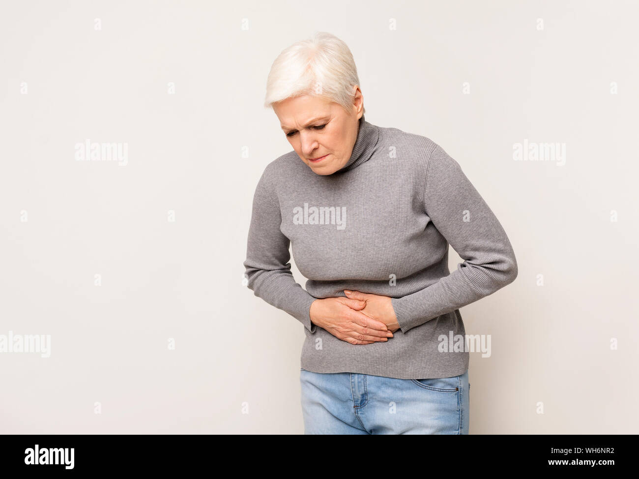 Infelice donna senior holding dello stomaco, che soffrono di dolore addominale Foto Stock