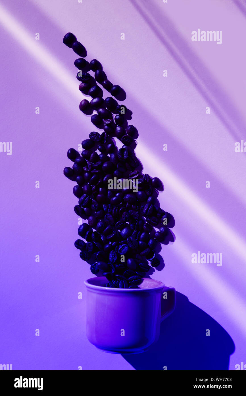 Tendenza neon color corallo con tazza di caffè effondere i fagioli con ombre su sfondo viola. Lay piatto. Vista dall'alto. Il minimalismo, il concetto di caffè. La Pop art sti Foto Stock