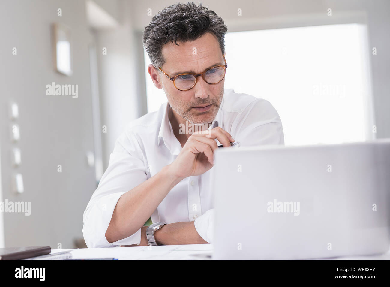 Imprenditore lavora in luminoso ufficio con computer portatile Foto Stock