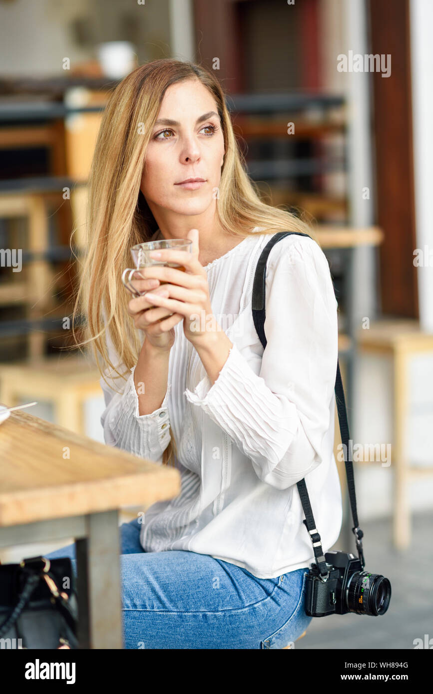 Donna bere il tè seduti ad un tavolo per esterno in un cafe Foto Stock