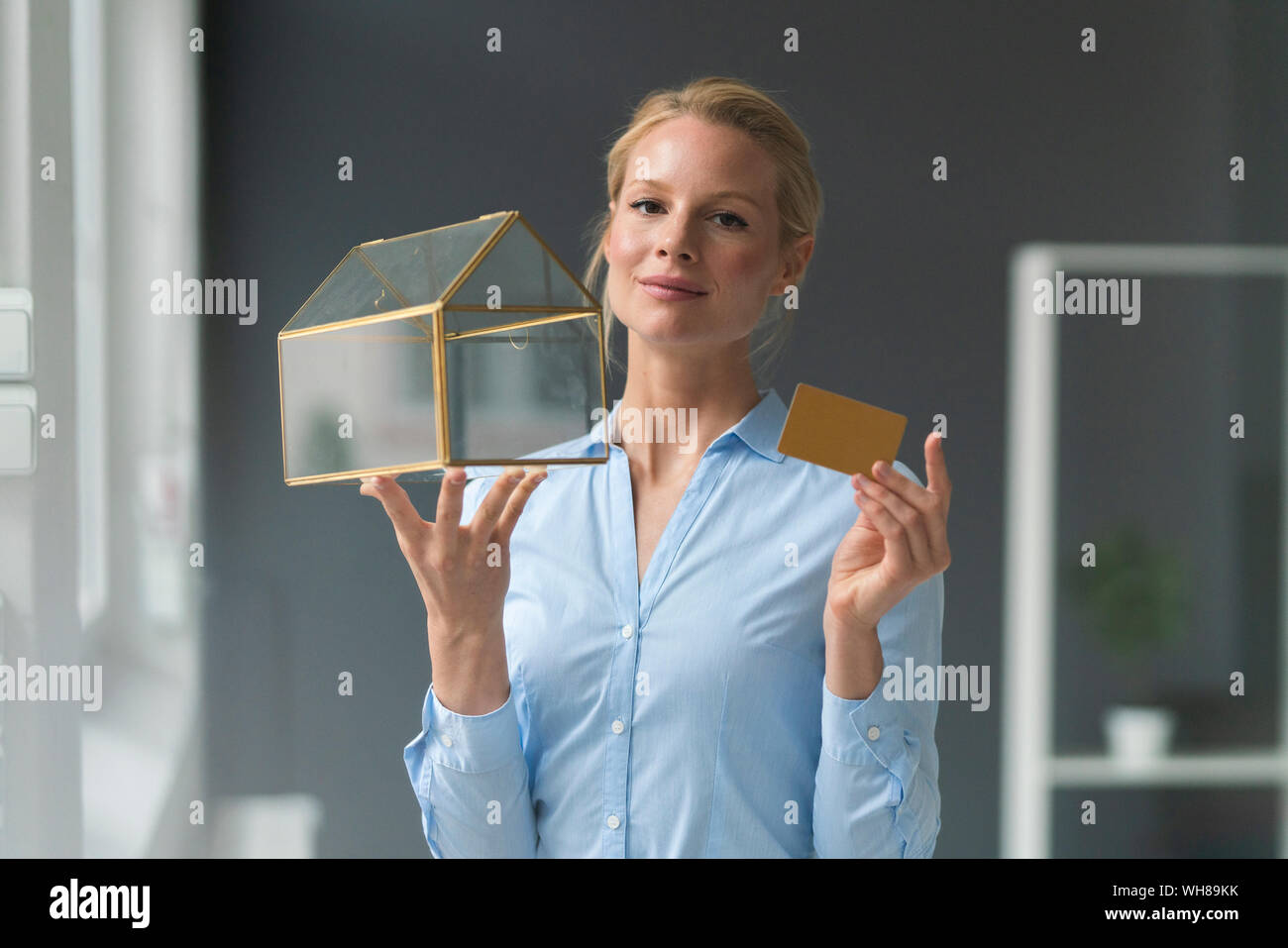 Sorridente giovane imprenditrice azienda casa di vetro modello e carta di credito Foto Stock
