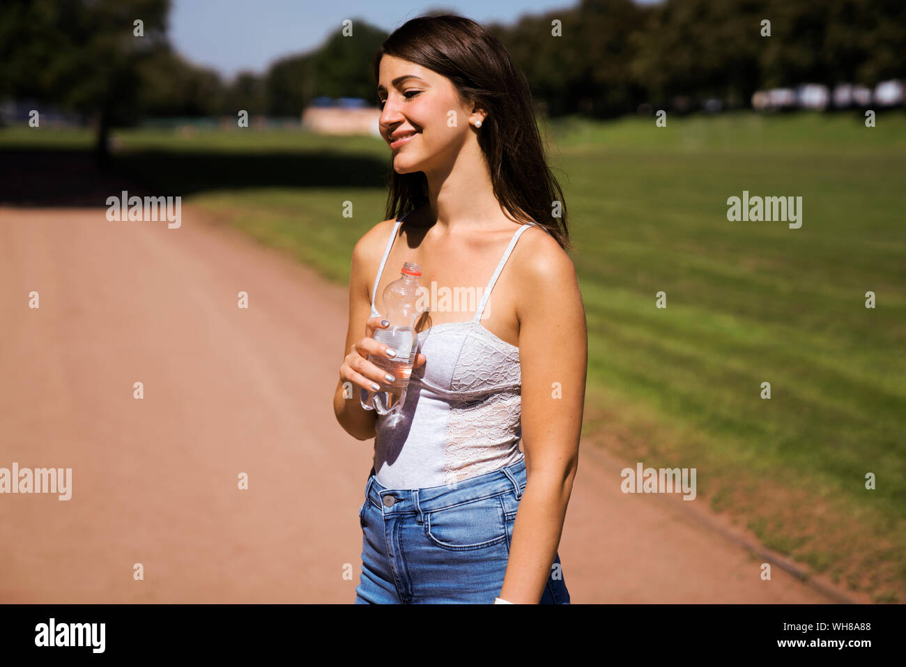 Ritratto di giovane donna che indossa top bianco in un parco in estate Foto Stock