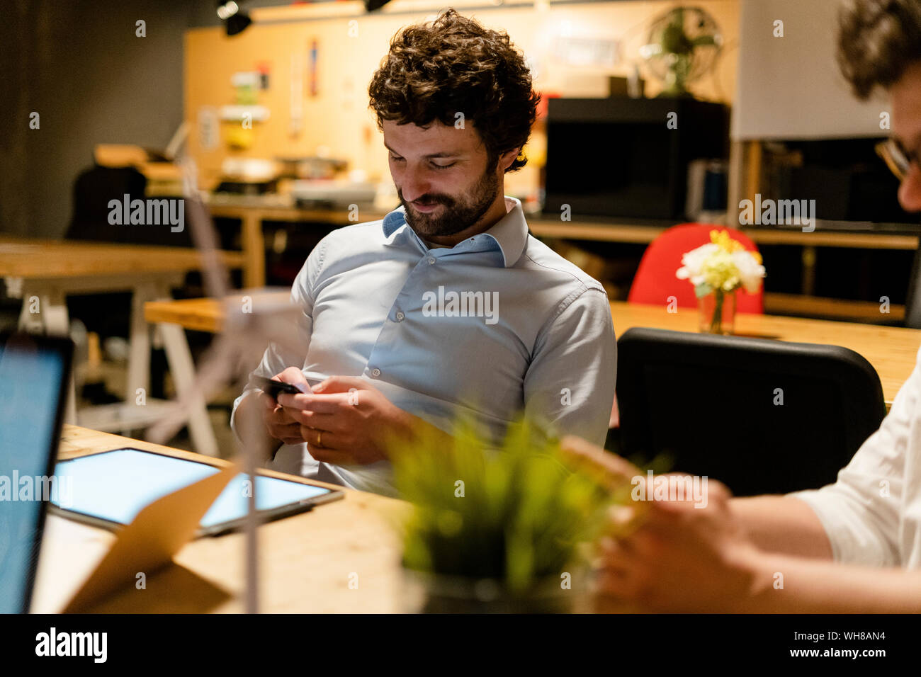 Imprenditore tramite telefono cellulare alla scrivania in ufficio Foto Stock