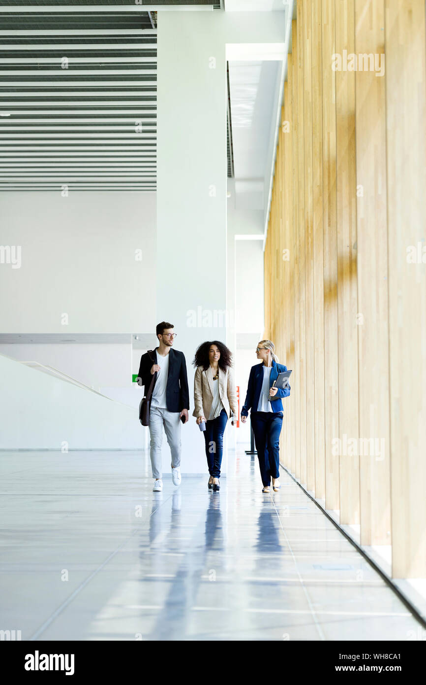 Young business la gente camminare e parlare in un corridoio Foto Stock