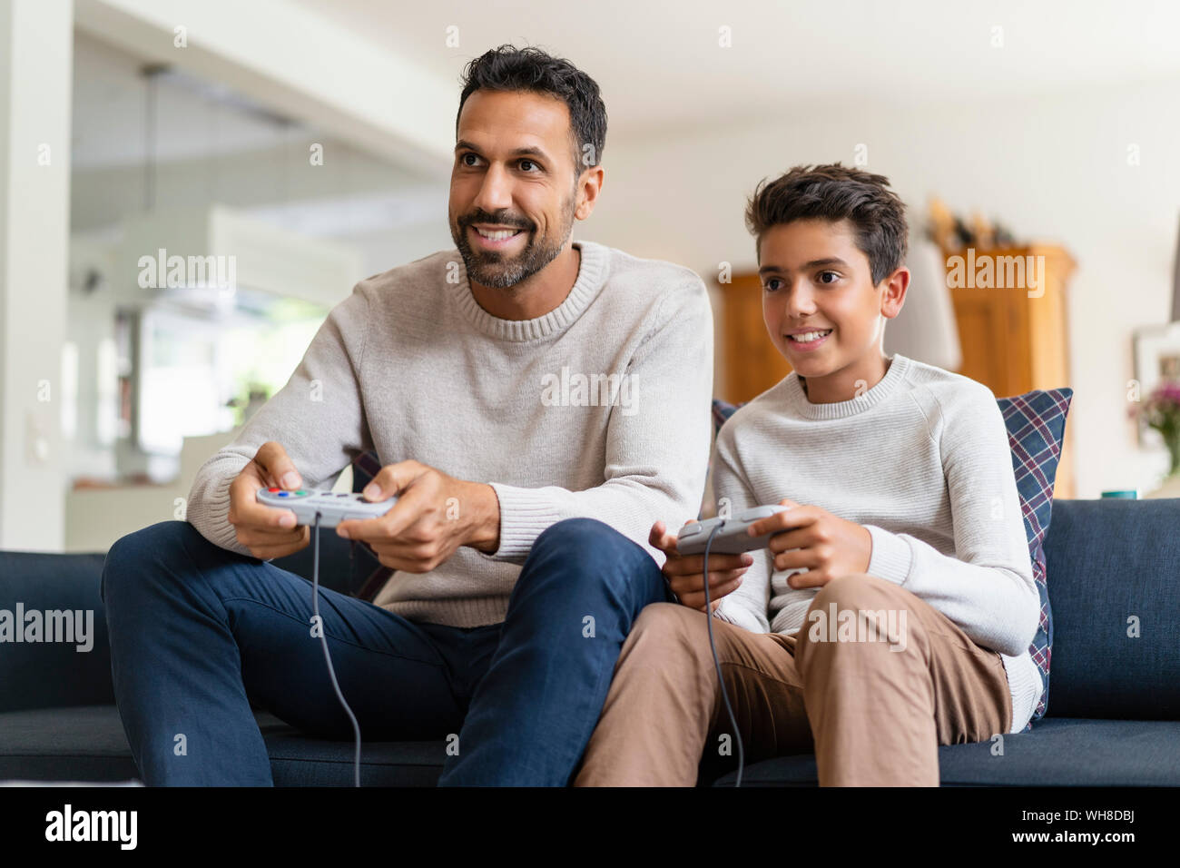 Felice padre e figlio la riproduzione del video gioco sul divano nel soggiorno Foto Stock