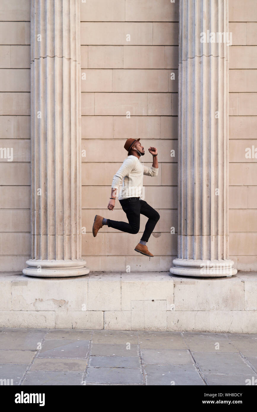 Metà uomo adulto ascoltando musica e jumping Foto Stock