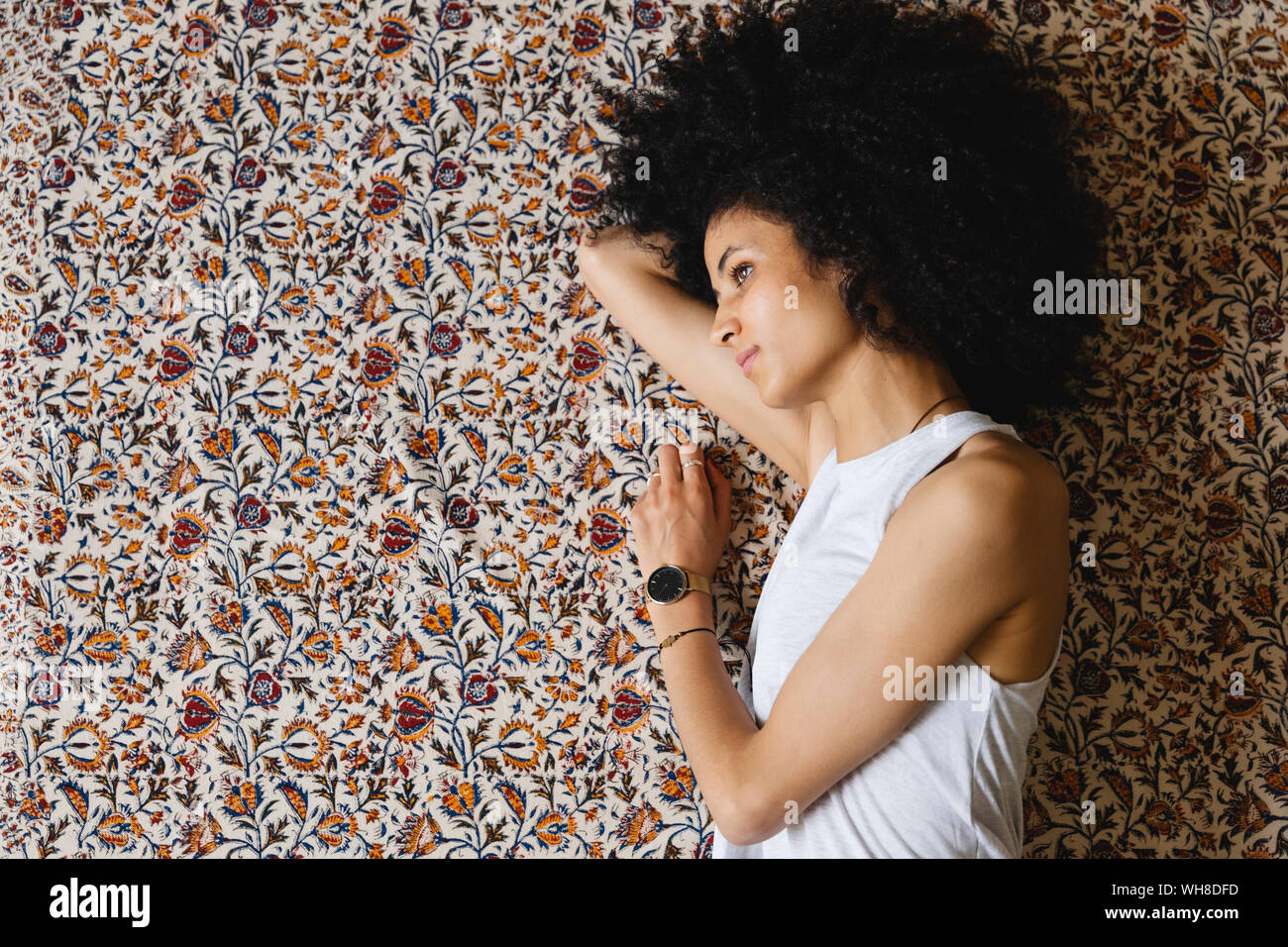 Giovane donna giacente sul suo lato sul tappeto Foto Stock