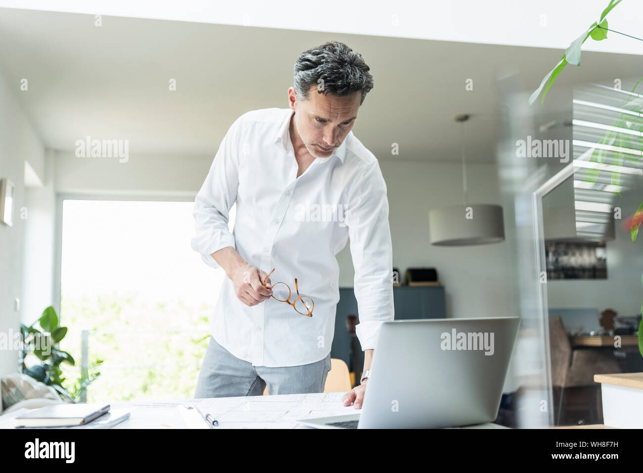 Architetto lavora sul progetto in un luminoso ufficio con computer portatile Foto Stock