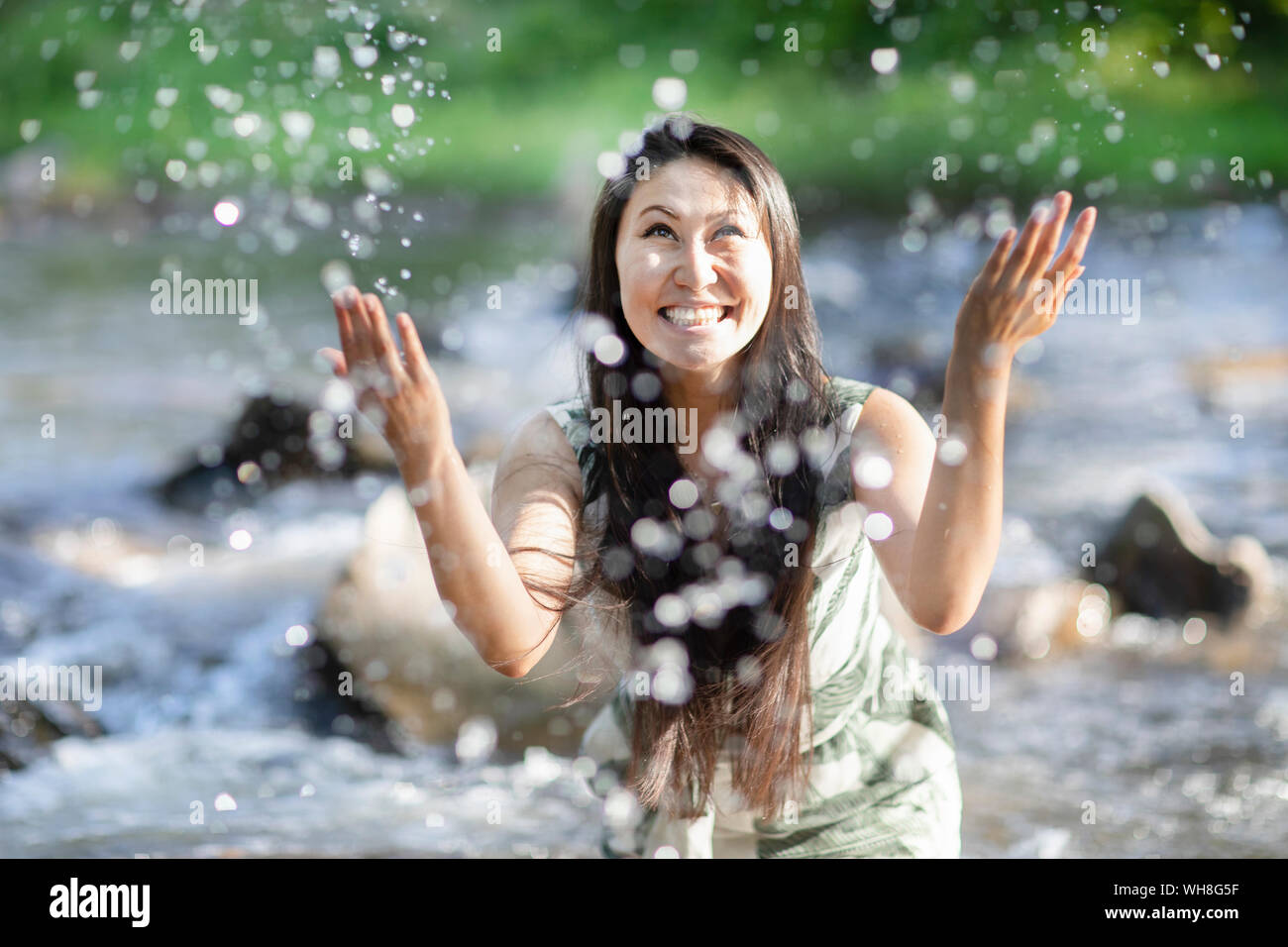 Giovane donna spruzzi in un fiume Foto Stock