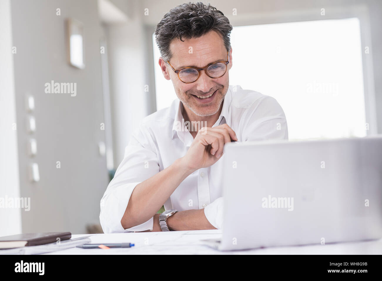 Imprenditore lavora in luminoso ufficio con computer portatile Foto Stock