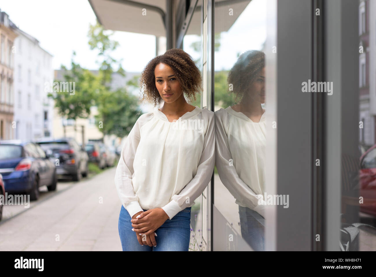 Ritratto di giovane donna appoggiata contro la finestra di visualizzazione Foto Stock