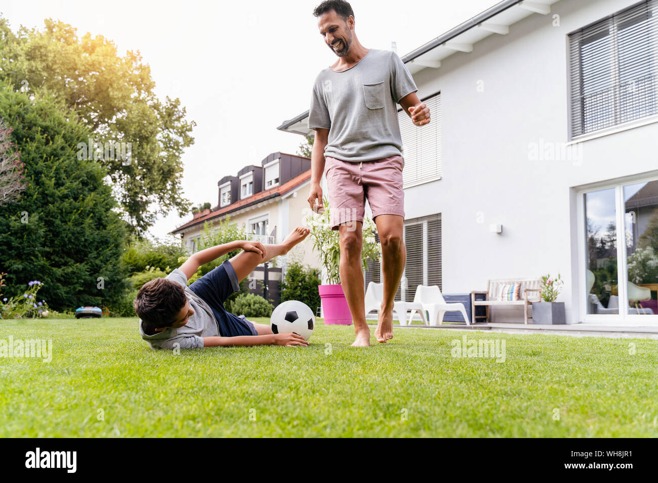 Padre e figlio a giocare a calcio in giardino Foto Stock