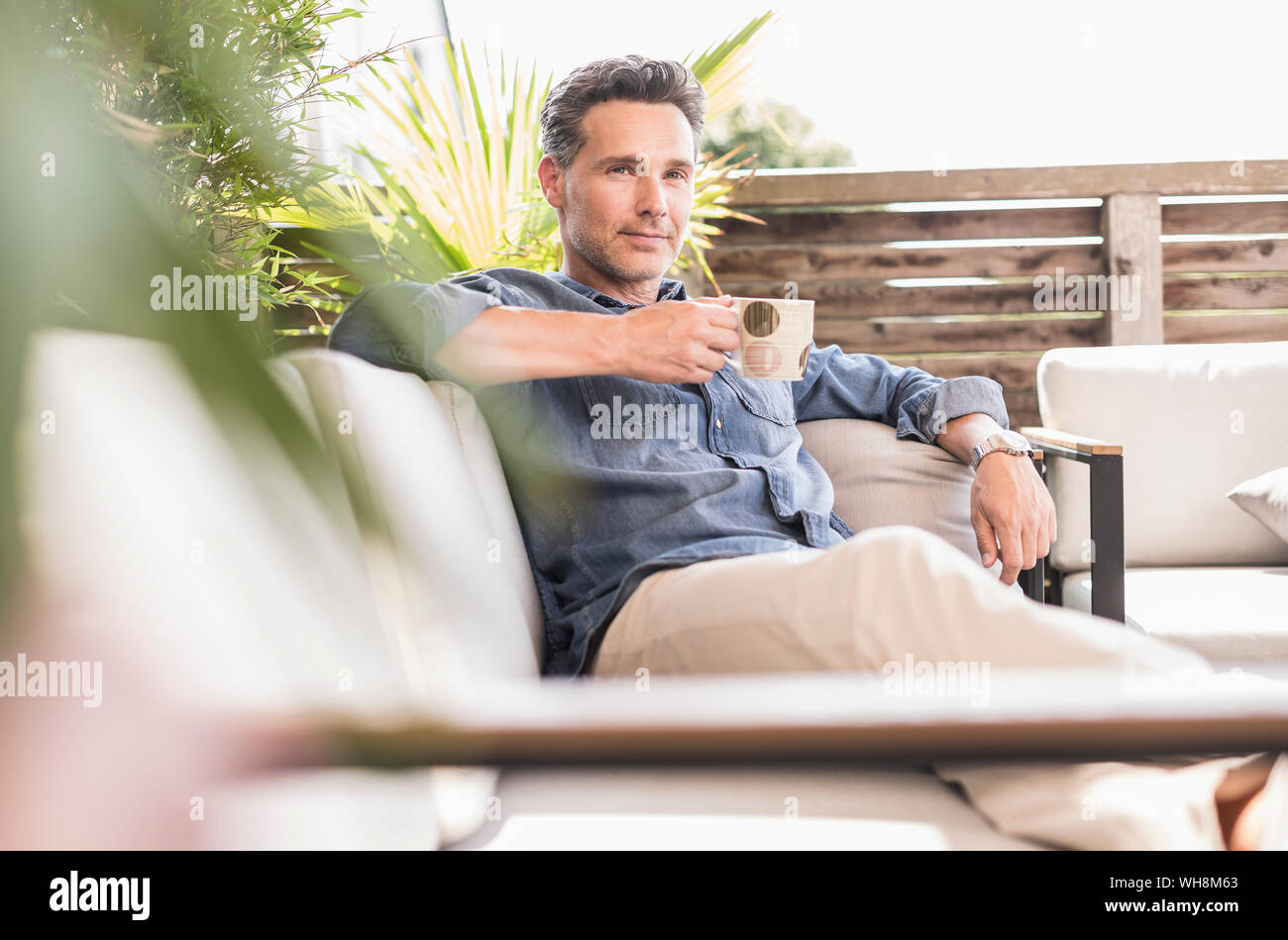 Fiducioso uomo rilassarsi sulla terrazza, a bere caffè Foto Stock