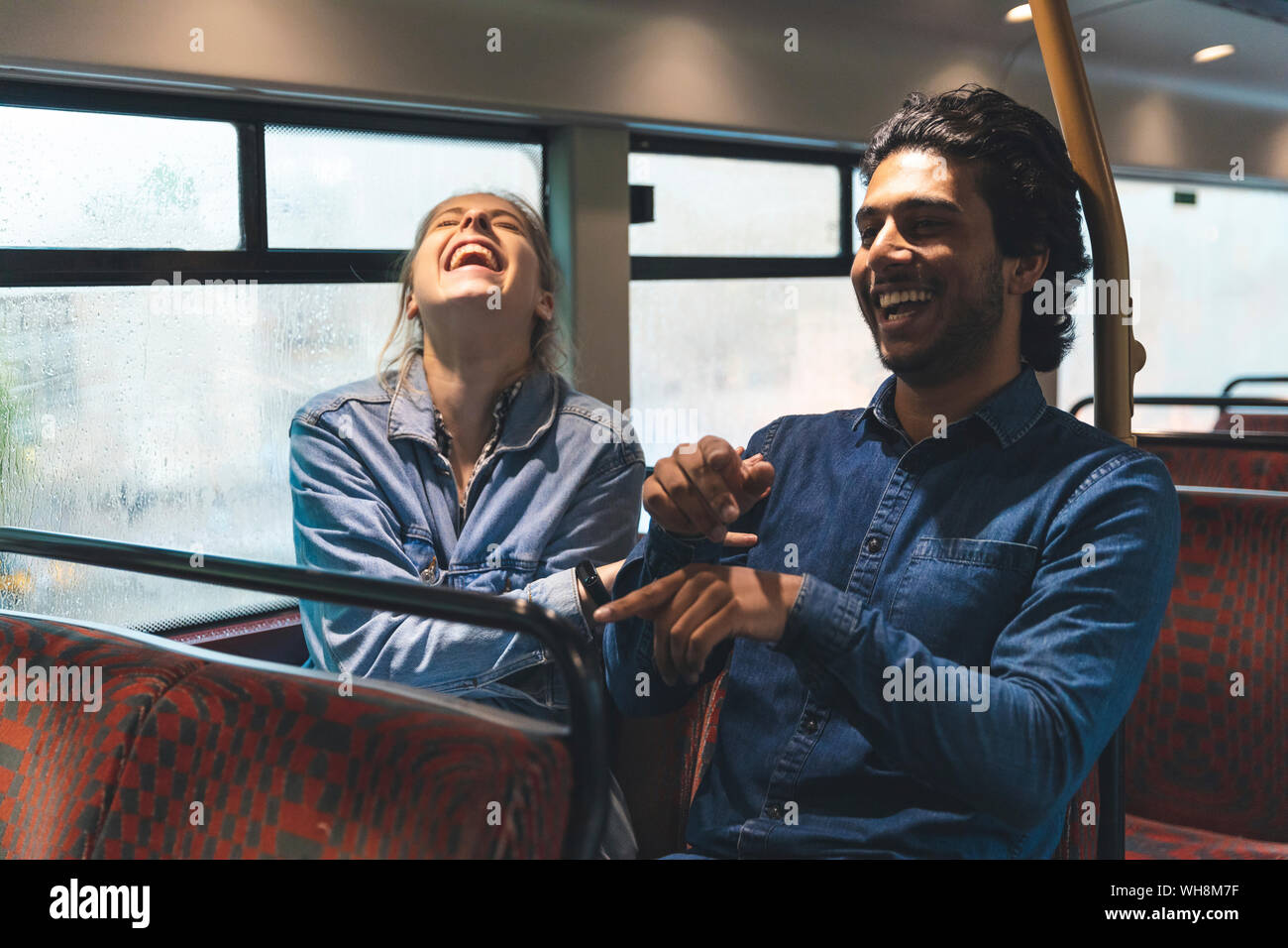 Coppia giovane viaggiando in autobus sul giorno di pioggia divertendosi, London, Regno Unito Foto Stock