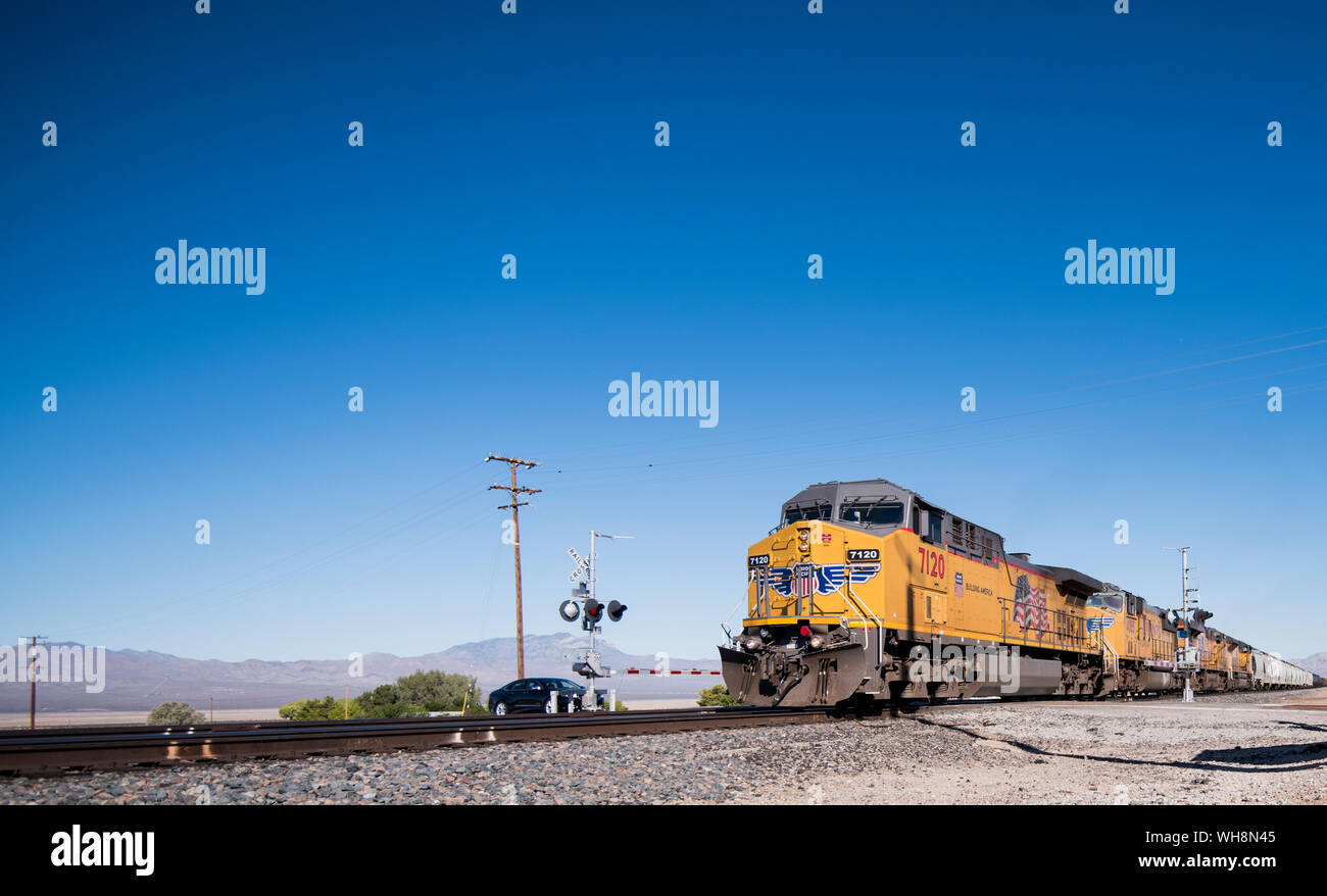 Un Union Pacific treno merci passa la ferrovia attraversando in Nipton, California, il 30 agosto 2019. Foto Stock