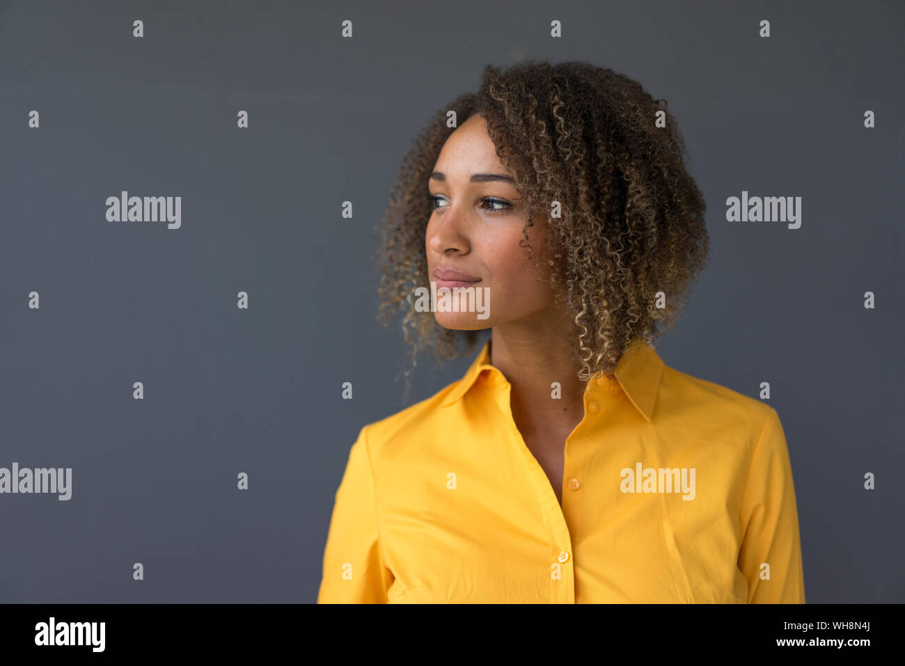 Ritratto di giovane donna indossa maglietta gialla guardando a distanza Foto Stock